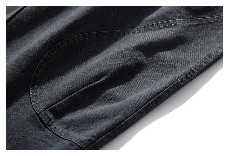 Close-up of a curved stitched pocket on charcoal trousers.