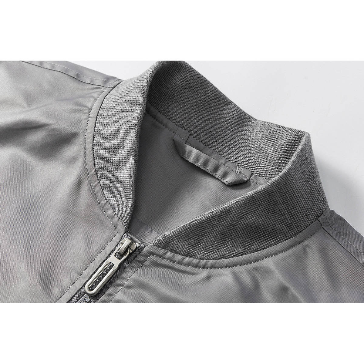 Close-up of a gray jacket’s ribbed stand collar and front zipper.