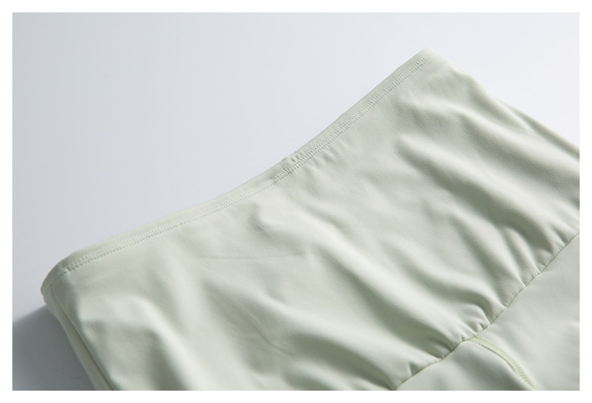 Close-up of a pale mint garment panel with a curved stitched edge and seam.