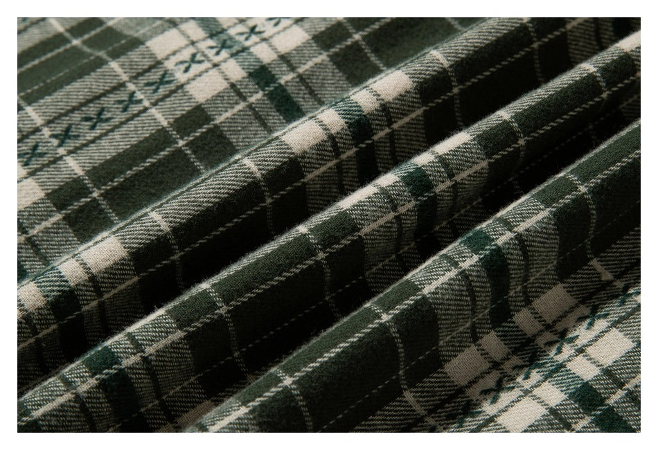 Close-up of green, cream, and black plaid fabric arranged in several folds.