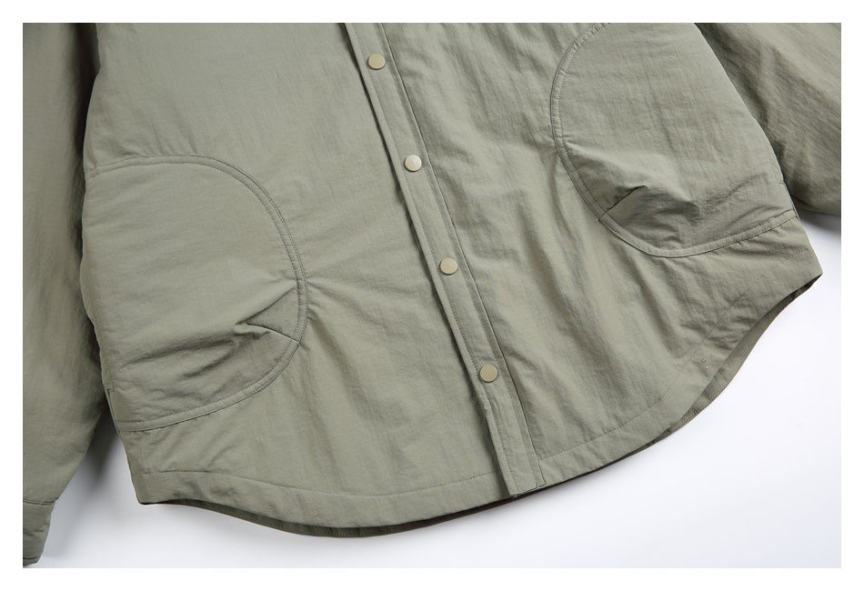 Close-up of the gray-green jacket's front snap buttons, curved lower pockets and hem.