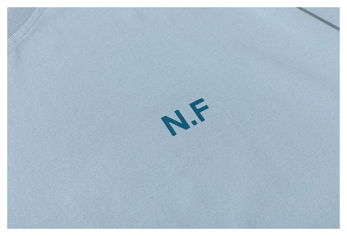 Close-up of the teal N.F print on the chest of a light blue T-shirt.
