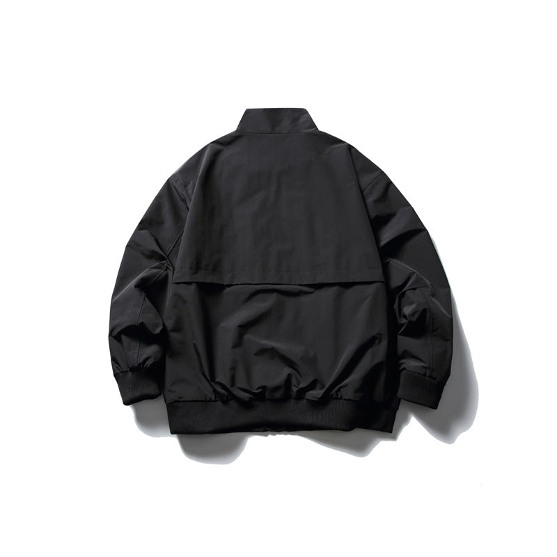 Back view of a black jacket with a stand collar, shoulder yoke, gathered hem and ribbed cuffs.