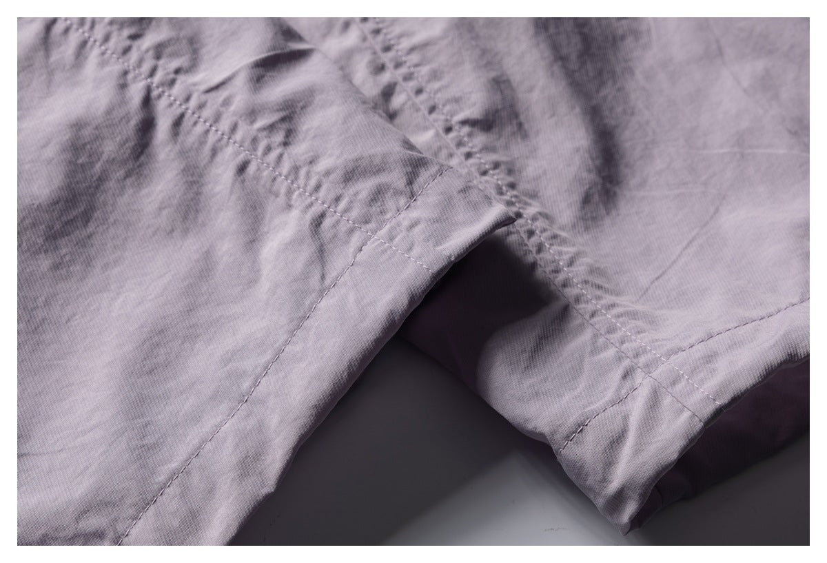 Close-up of stitched seams and a folded hem on mauve garment fabric.