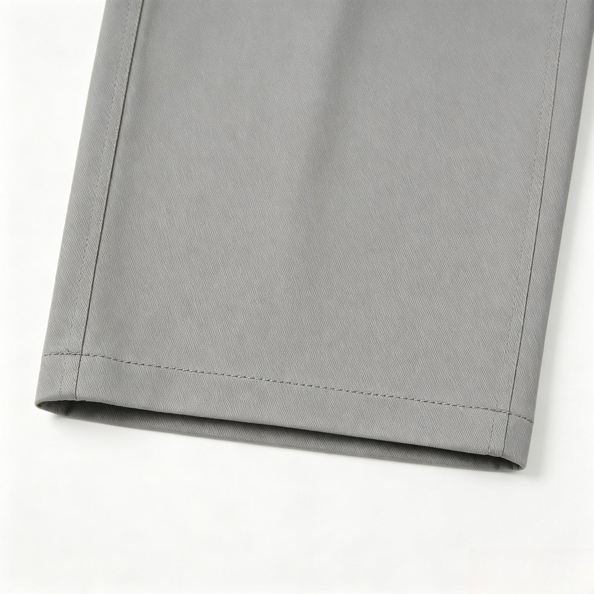 Close-up of a gray trouser leg hem with visible stitching on a white background.