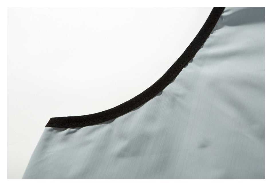 Close-up of black binding along the armhole of a pale blue-gray vest.
