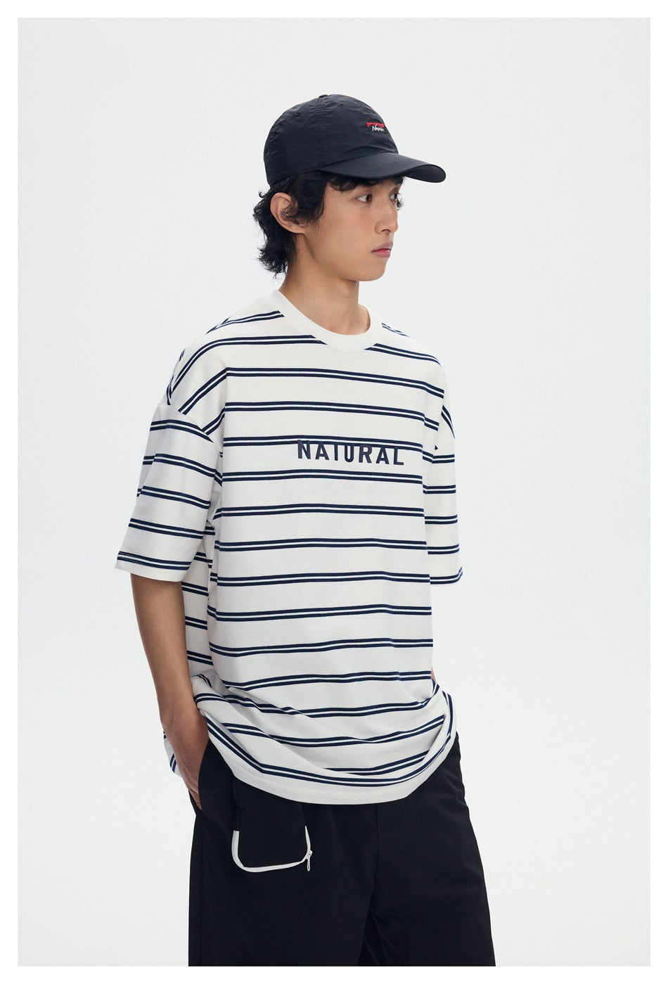 Front view of a model wearing an oversized ivory T-shirt with navy horizontal stripes and NATURAL lettering.