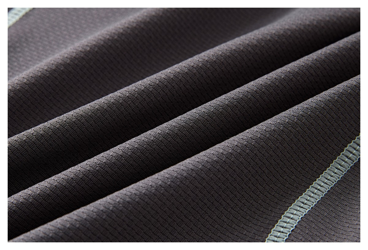 Close-up of dark charcoal textured fabric gathered into folds, with a pale gray-blue stitched seam.