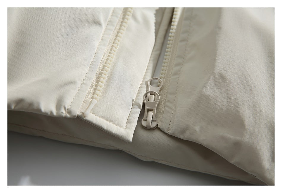 Close-up of the ivory jacket's front zipper and overlapping placket.