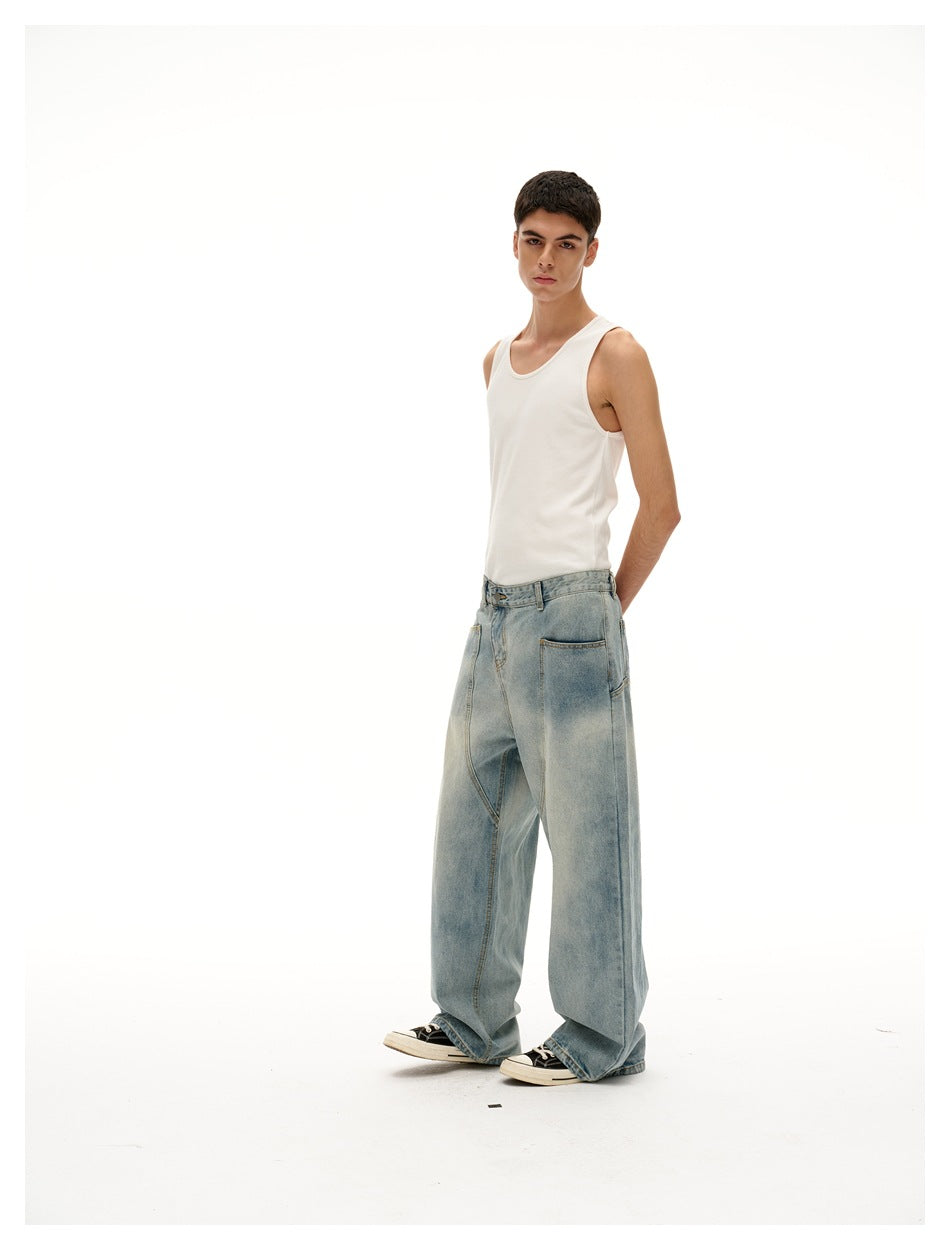 Model in a white tank top and oversized light-wash jeans, turned to show the side and a rear pocket.