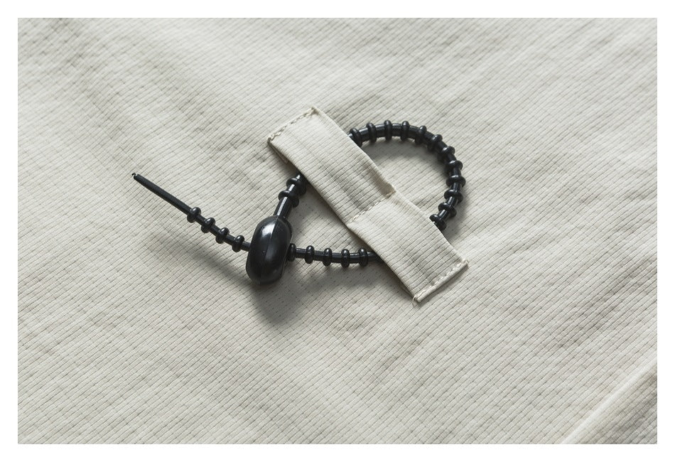 Black segmented drawcord and fabric loop detail on light beige ribbed garment fabric.