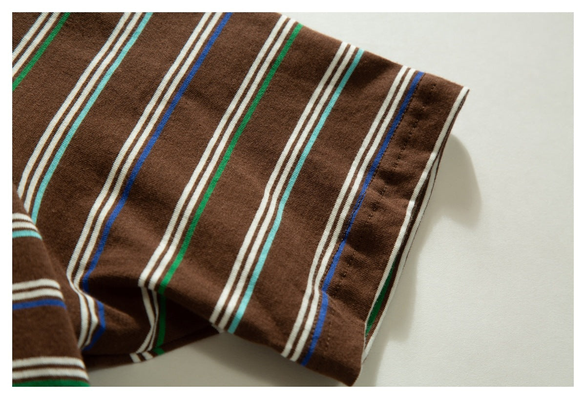 Close-up of brown garment fabric with vertical cream, turquoise, green and blue stripes and a stitched edge.