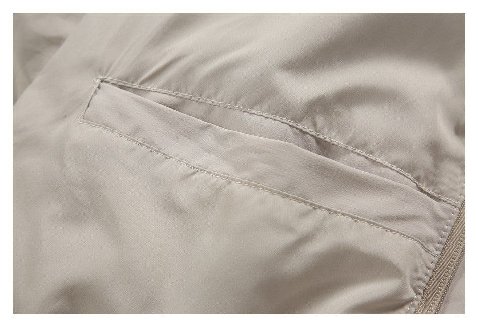 Close-up of a light beige garment's stitched pocket and adjacent zipper.