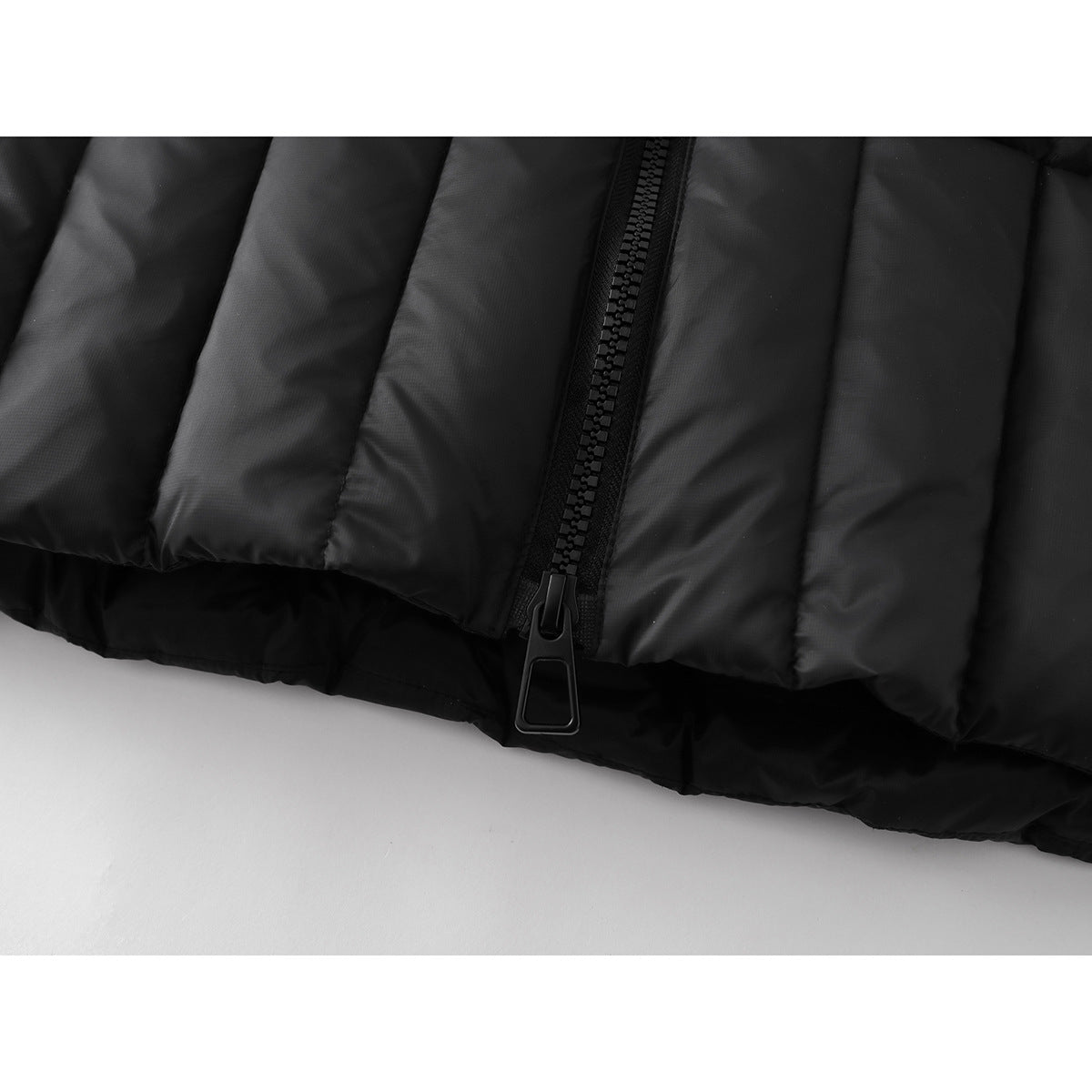 Close-up of the black jacket's lower front zipper, pull and padded hem.