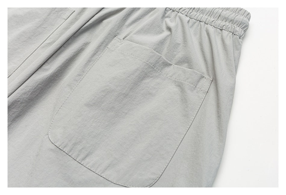 Close-up of a large patch pocket and elastic waistband on light gray shorts.