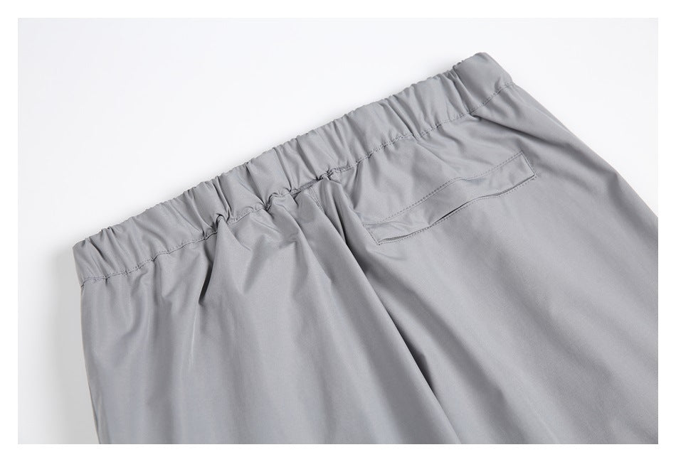 Close-up of the gathered elastic waistband and a welt pocket on the back of gray pants.