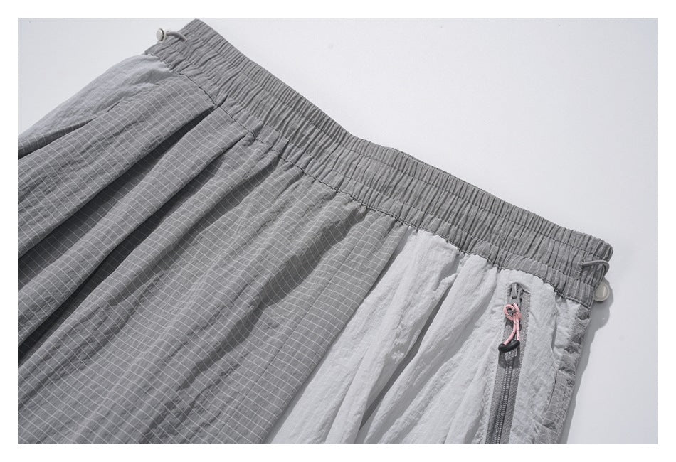 Close-up of the pants' gathered waistband, gray grid-patterned panels and zip pocket with a pink pull cord.