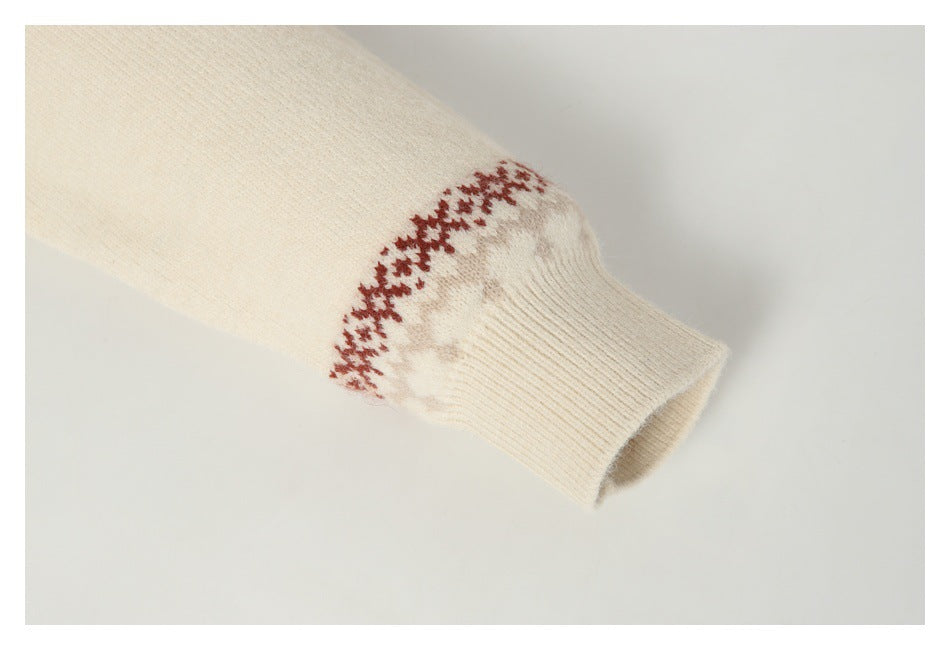Close-up of a cream sweater sleeve ending in a ribbed cuff, with a red and gray patterned band.