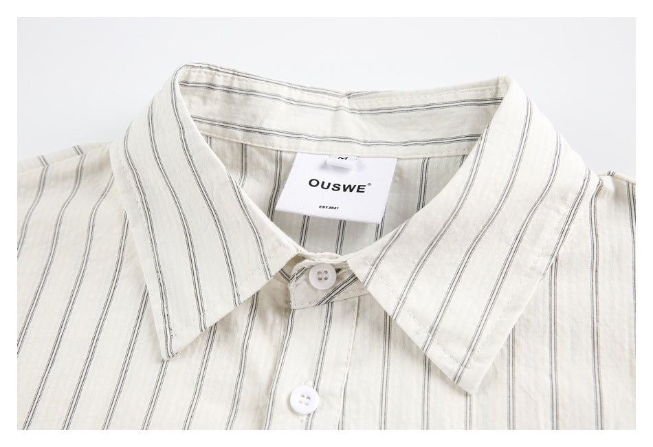 Close-up of the collar and white buttons on an off-white shirt with thin dark stripes.