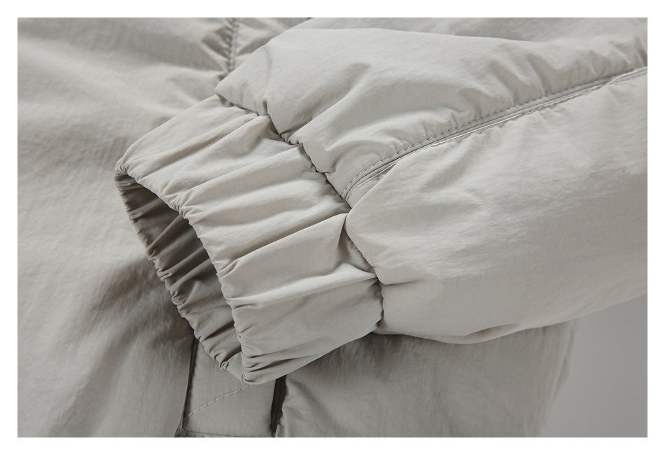 Close-up of the gathered cuff and sleeve stitching on a light gray-beige jacket.