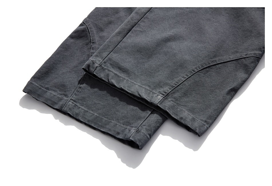 Close-up of the stitched hems and lower legs of charcoal trousers.