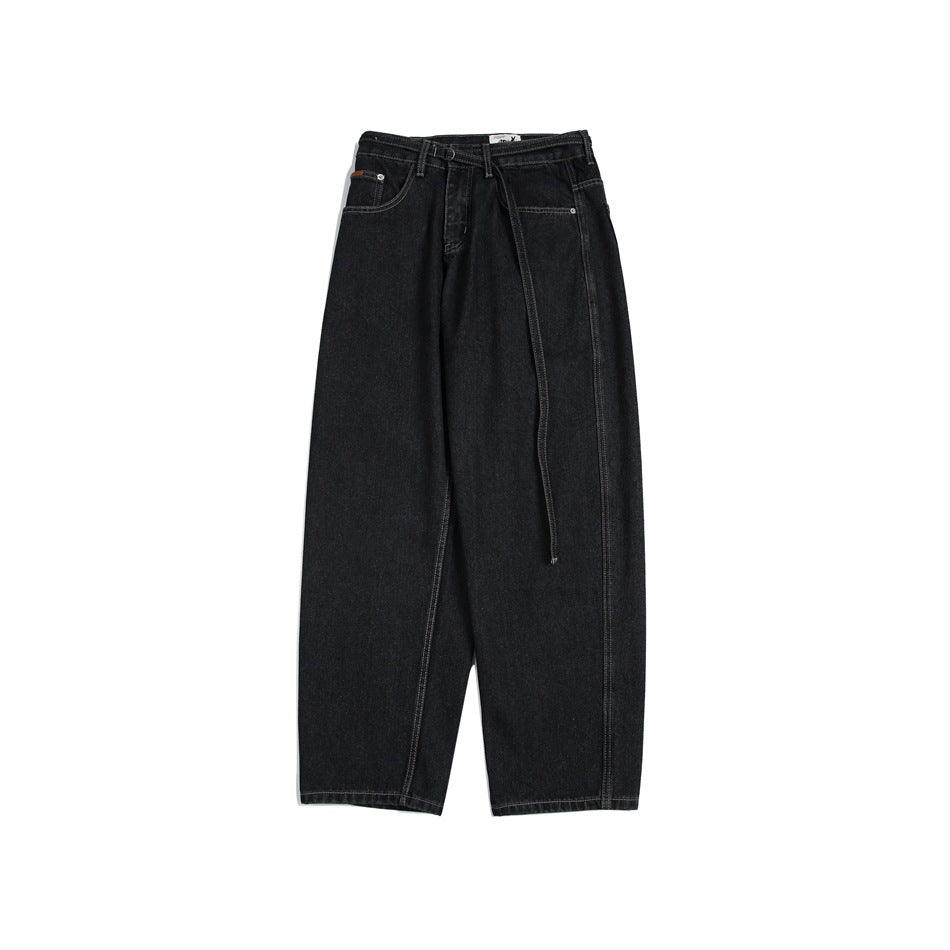 Front view of black, wide-leg jeans with a long matching belt hanging from the waist.