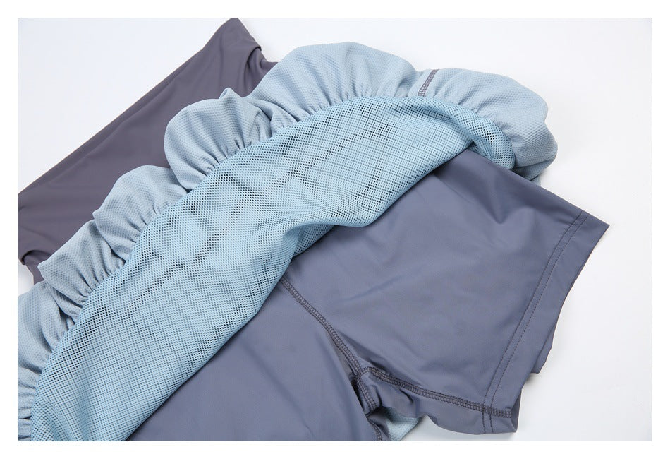 Close-up of light blue mesh lining gathered over a slate-gray athletic skirt.
