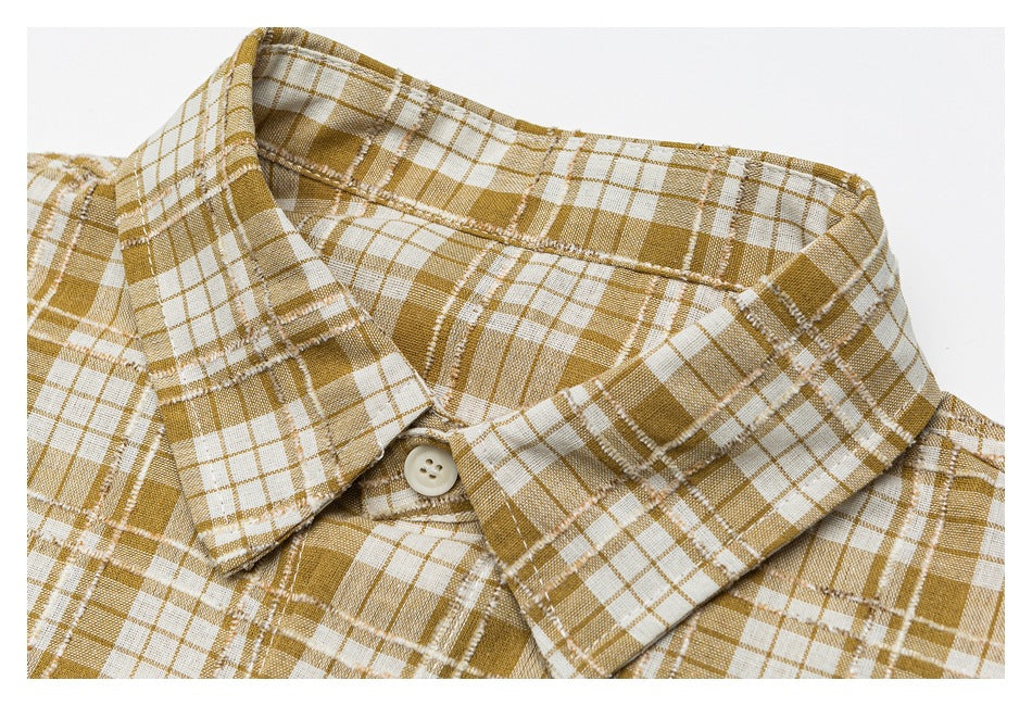 Close-up of a mustard-and-white plaid shirt collar and a cream button.
