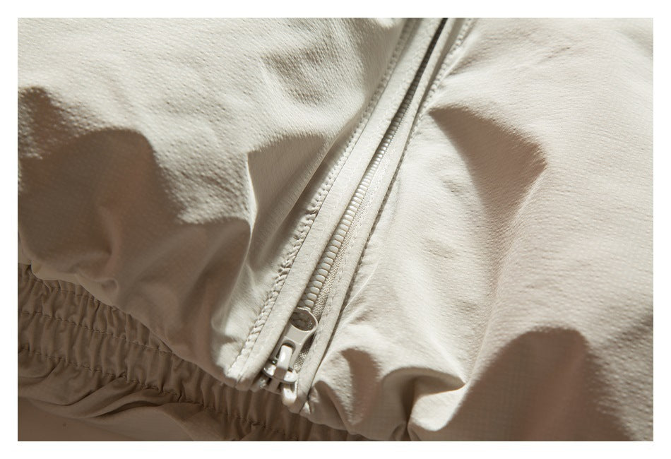 Close-up of a cream garment zipper beside a gathered elastic edge.