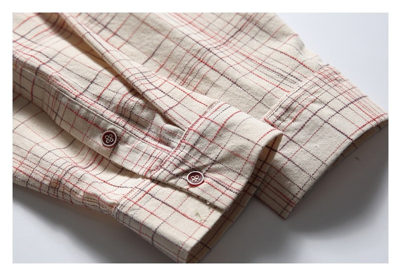 Close-up of the beige plaid shirt's cuff and sleeve with two dark buttons.