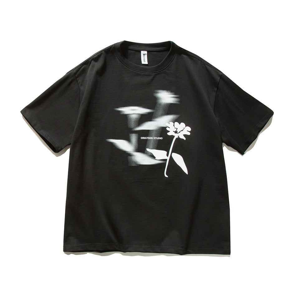 Black short-sleeve crew-neck T-shirt with blurred white flower silhouette graphic on the front, flat lay