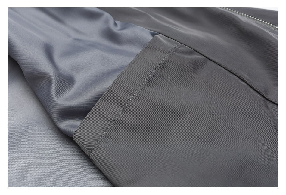 Close-up of a stitched seam joining dark gray fabric with a smooth gray lining.