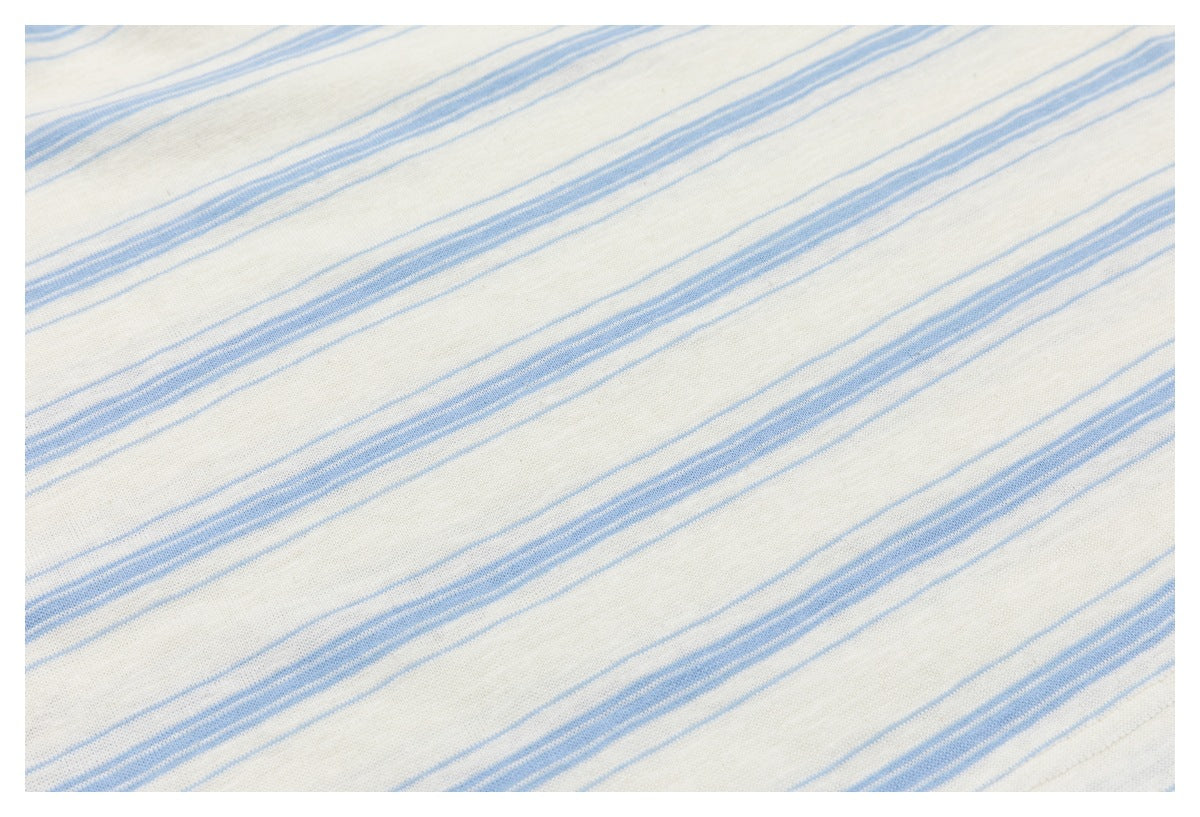 Close-up of off-white fabric with irregular narrow and broad pale blue stripes.