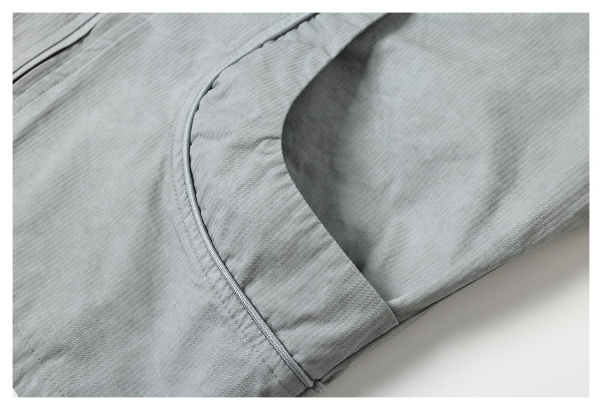 Close-up of light gray fabric with a curved, neatly piped pocket edge.