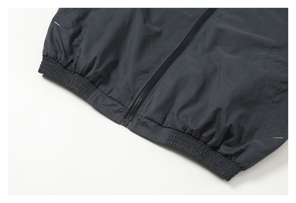 Close-up of a dark charcoal jacket hem, front zipper, and elasticized waistband.