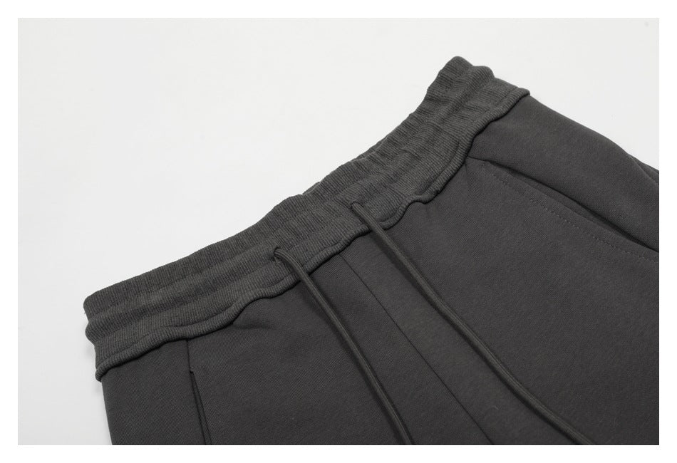 Close-up of charcoal pants showing the ribbed elastic waistband, drawstrings, and front pocket seam.