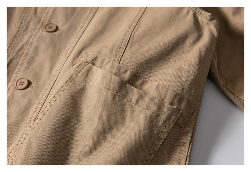 Close-up of a large front pocket on the tan jacket, with its button placket and stitched detailing visible.