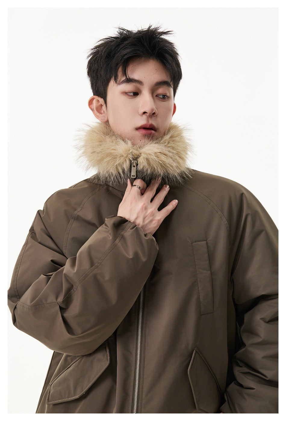 Model wearing a brown zip jacket with fluffy faux-fur-style collar, hand resting at the collar, close-up