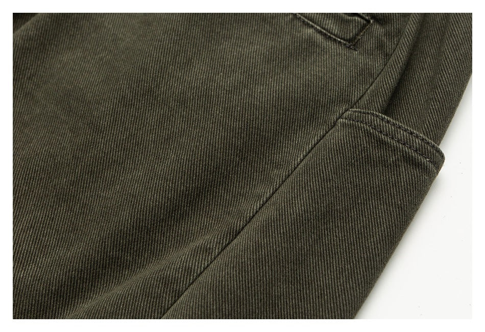 Close-up of dark olive trouser fabric and the stitched edge of a side utility pocket.