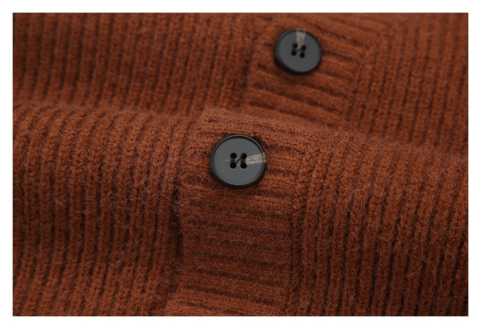 Close-up of two dark buttons and ribbed knit on a rust-brown cardigan.