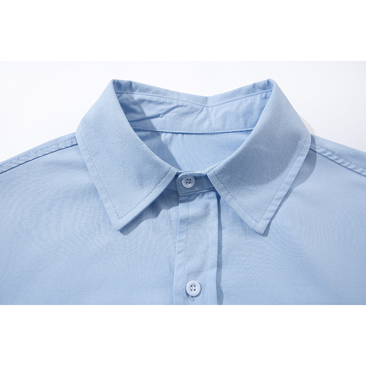Close-up of a light blue button-up shirt collar and front placket with white buttons.