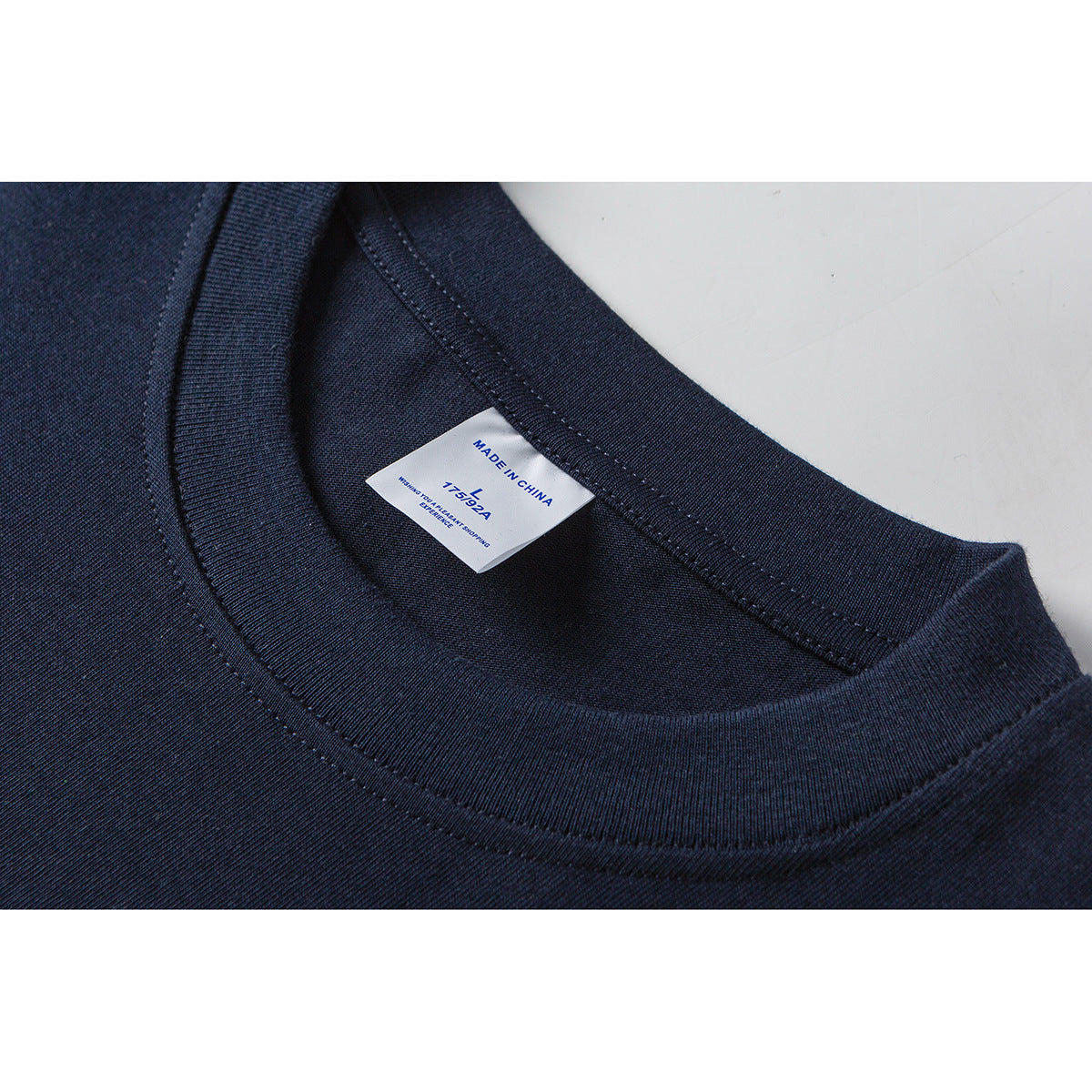 Close-up of a dark navy T-shirt’s ribbed crew neck and inner size label.