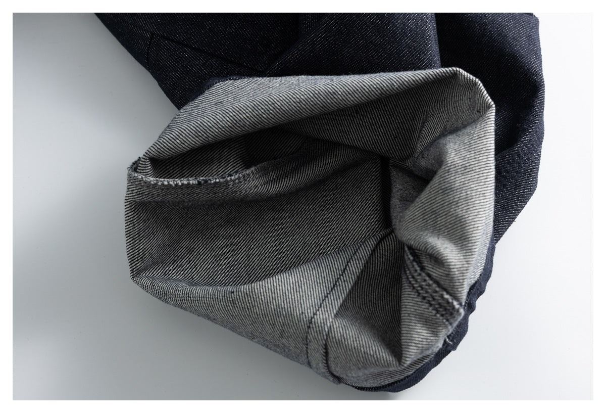 Close-up of a trouser leg cuff turned inside out, showing its gray diagonal-weave reverse and dark outer fabric.