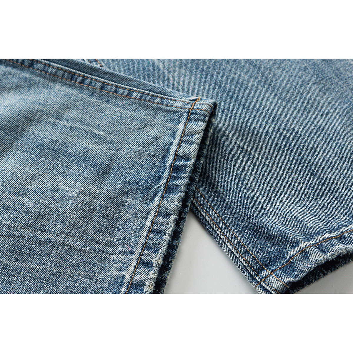 Close-up of blue denim jean legs showing the stitched seams and folded hems.