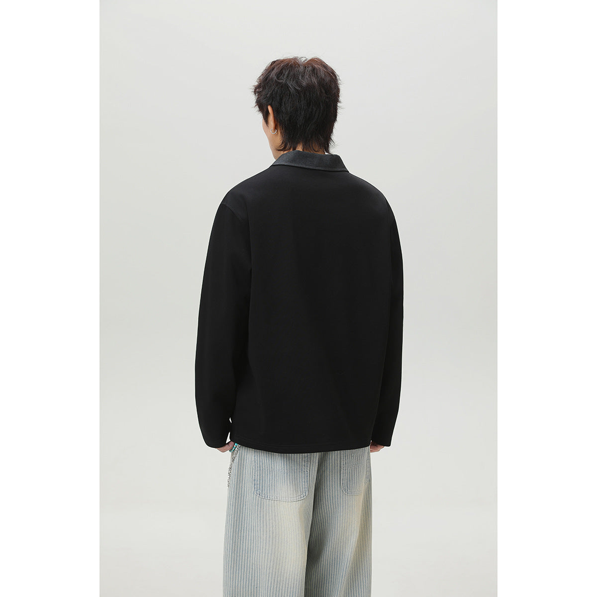 Back view of a person wearing a black long-sleeve top with a charcoal collar.