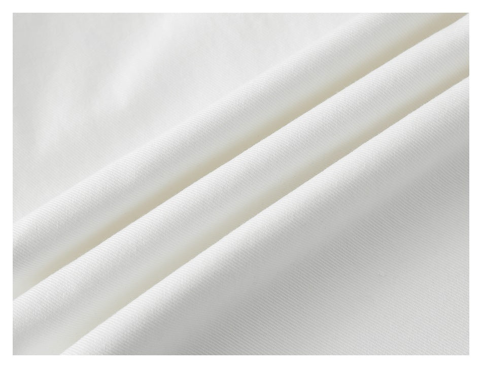 Close-up of white trouser fabric folded into soft diagonal ridges.