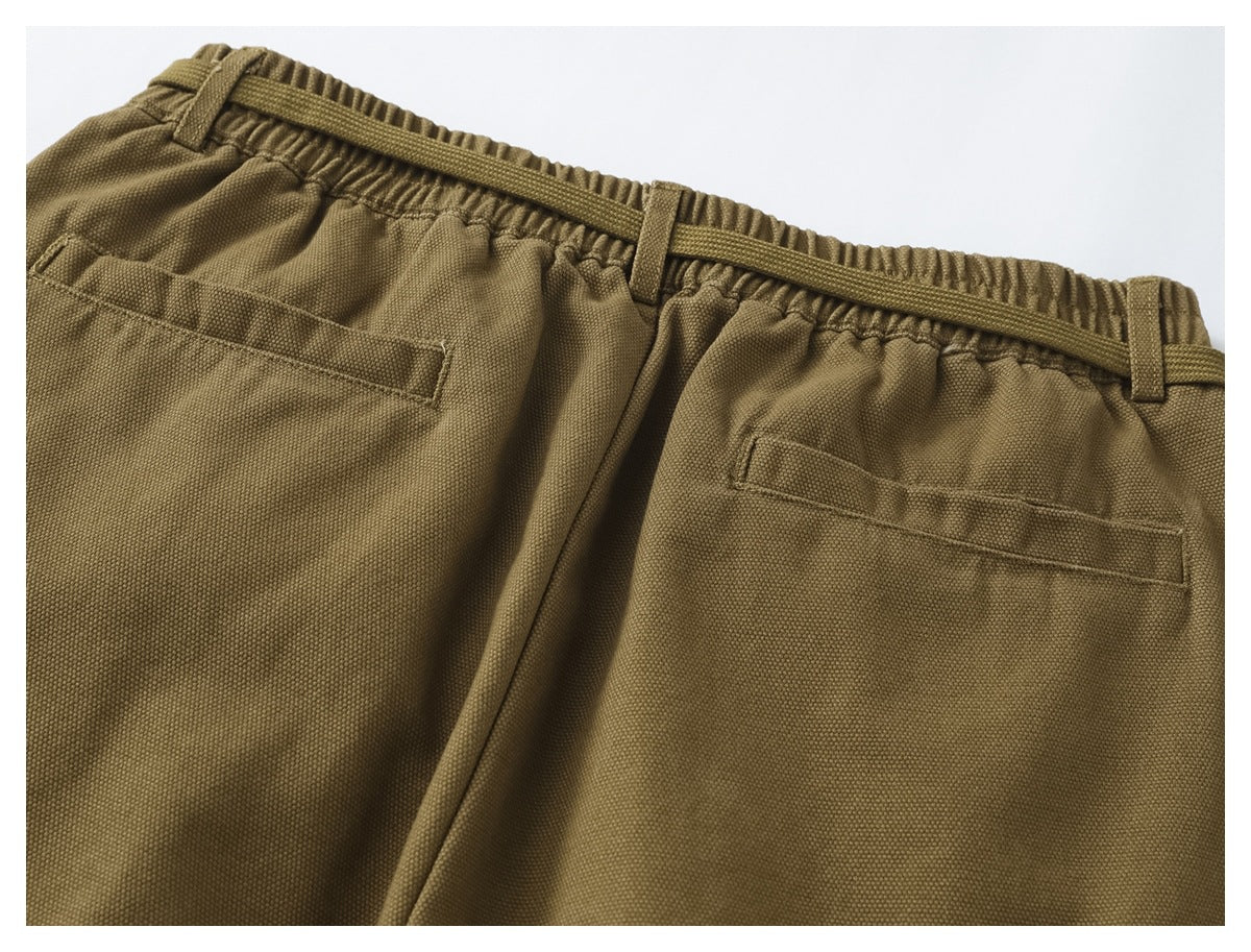 Cropped back view of olive-brown trousers showing an elastic waist, belt loops, and two welt pockets.