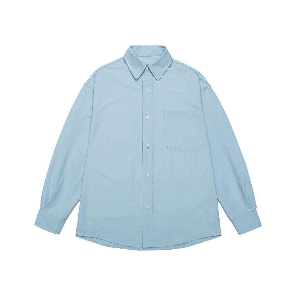 Light blue long-sleeve button-up shirt with pointed collar, chest pocket, and curved hem, shown from the front.