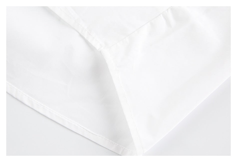 Close-up of white garment panels meeting at a stitched seam, with a folded edge visible.
