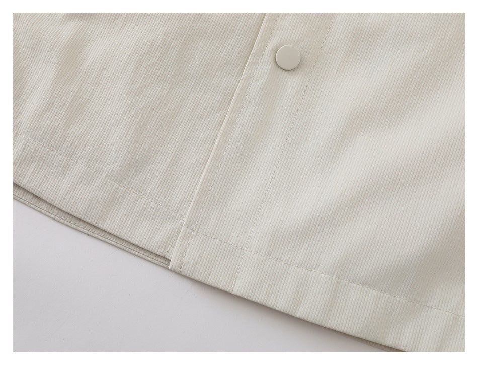 Close-up of the ivory garment's lower hem and front placket with a round snap button.